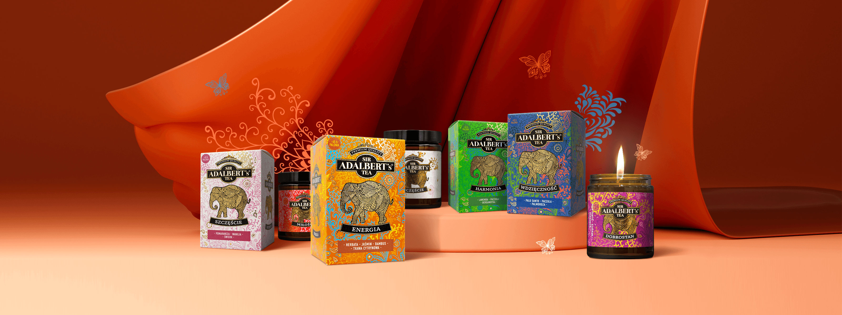 Kolorowe opakowania herbat Sir Adalbert's z motywem słonia na pomarańczowym tle z płonącą świecą