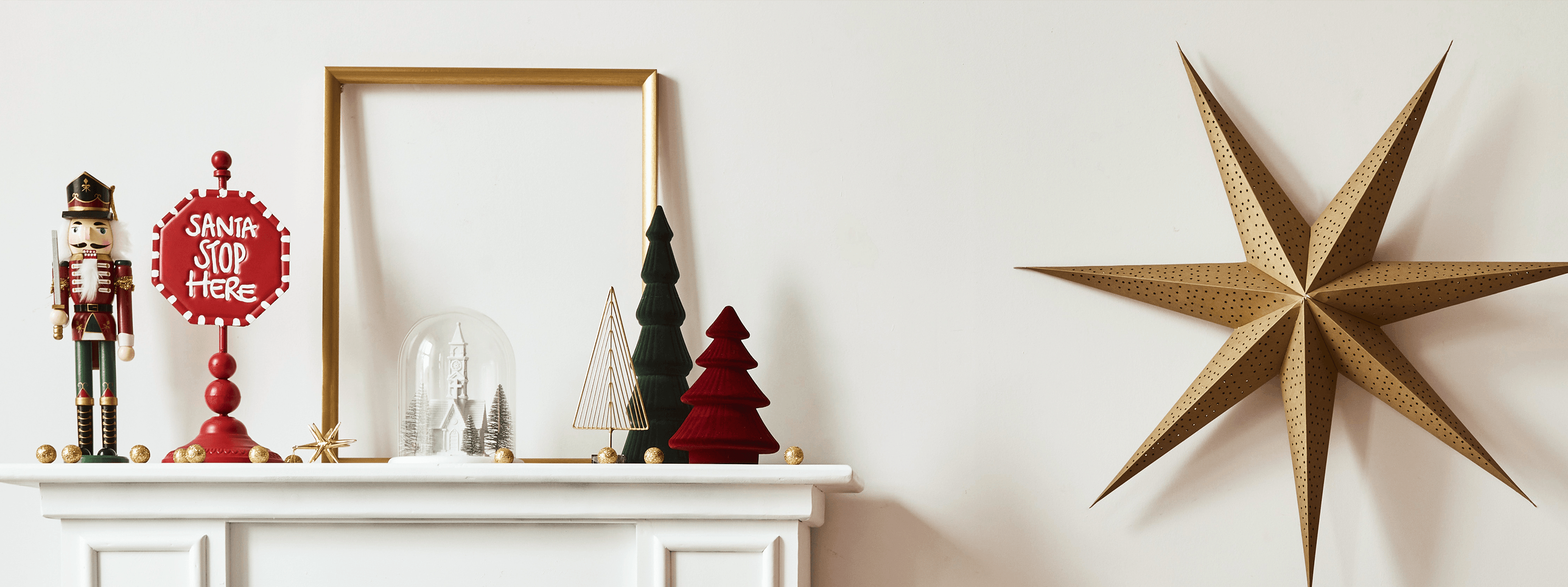 Dekoracje świąteczne na białym kominku z dziadkiem do orzechów, choinkami i gwiazdą