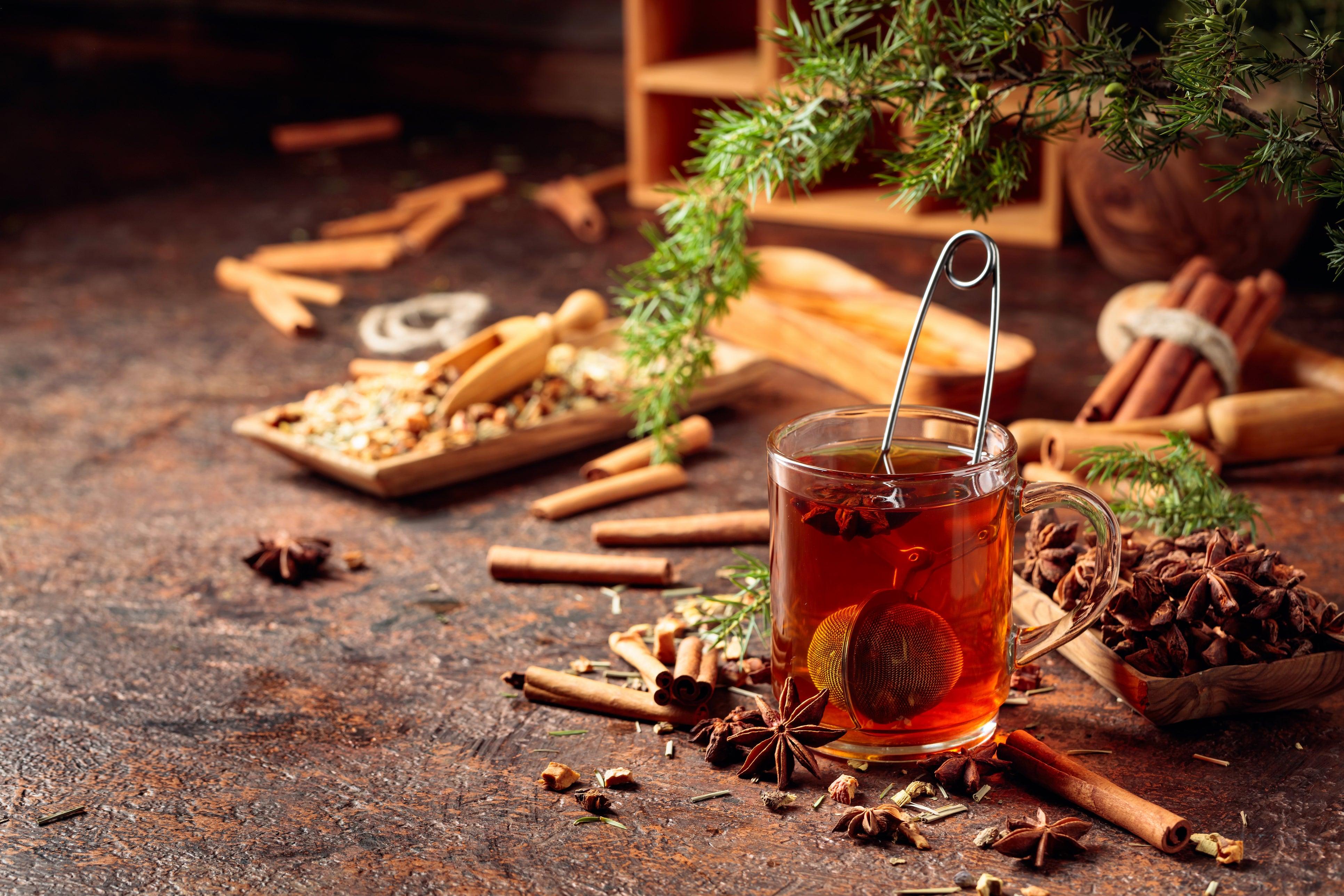 Herbata z owoców dzikiej róży w szklanym kubku z zaparzaczem, cynamon i anyż na drewnianym stole