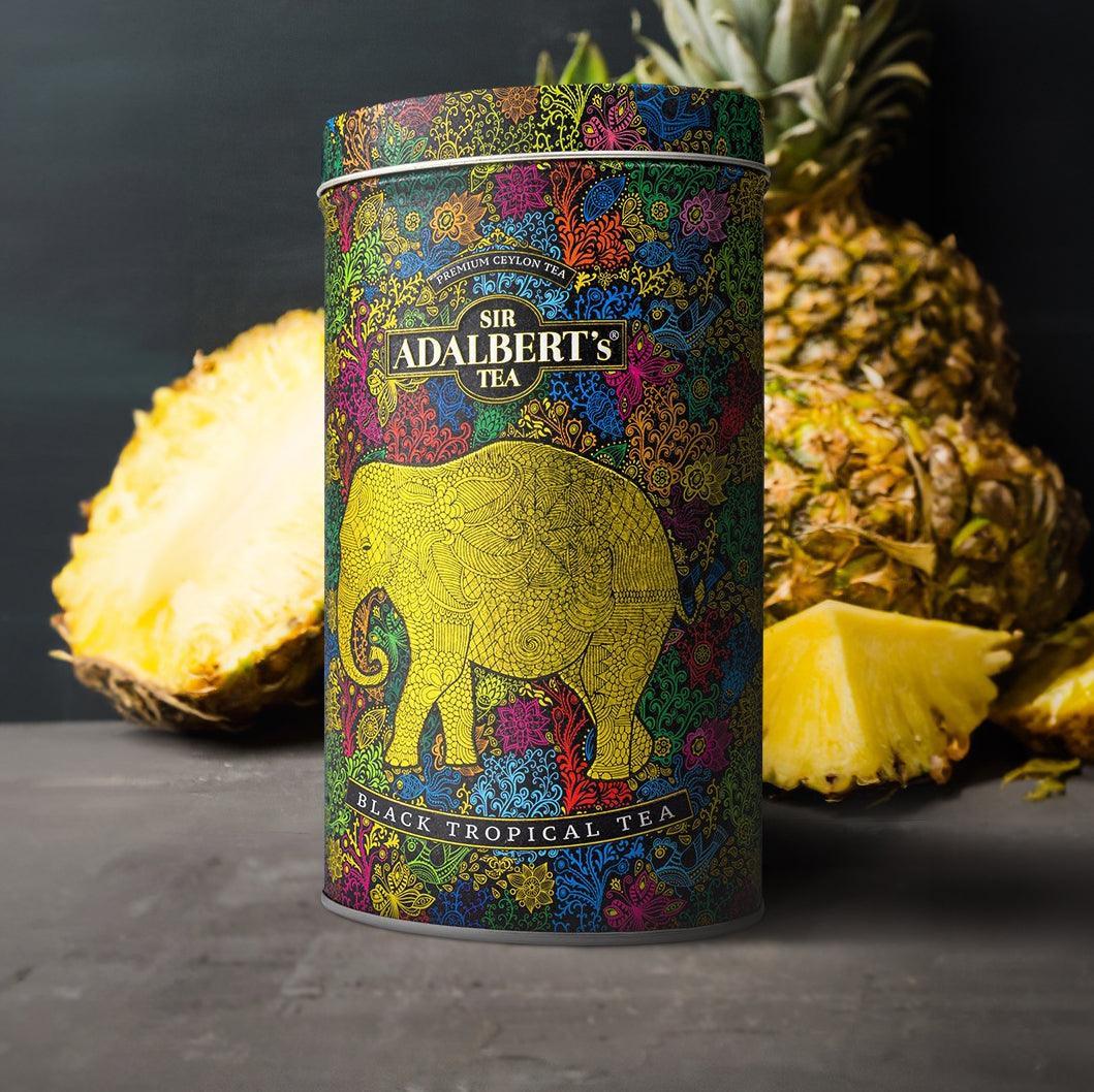 Puszka herbaty Sir Adalbert's Black Tropical Tea z kolorowym zdobieniem słonia, obok świeży ananas